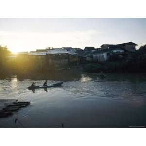  The Sun Sets Behind Waterfront Housing as People Paddle a 