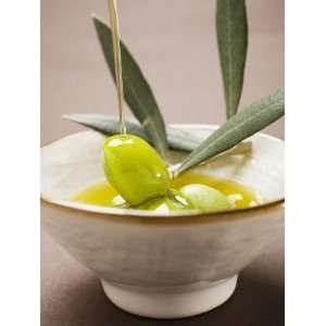 Pouring Olive Oil Over Olive Sprig with Green Olives Photographic 